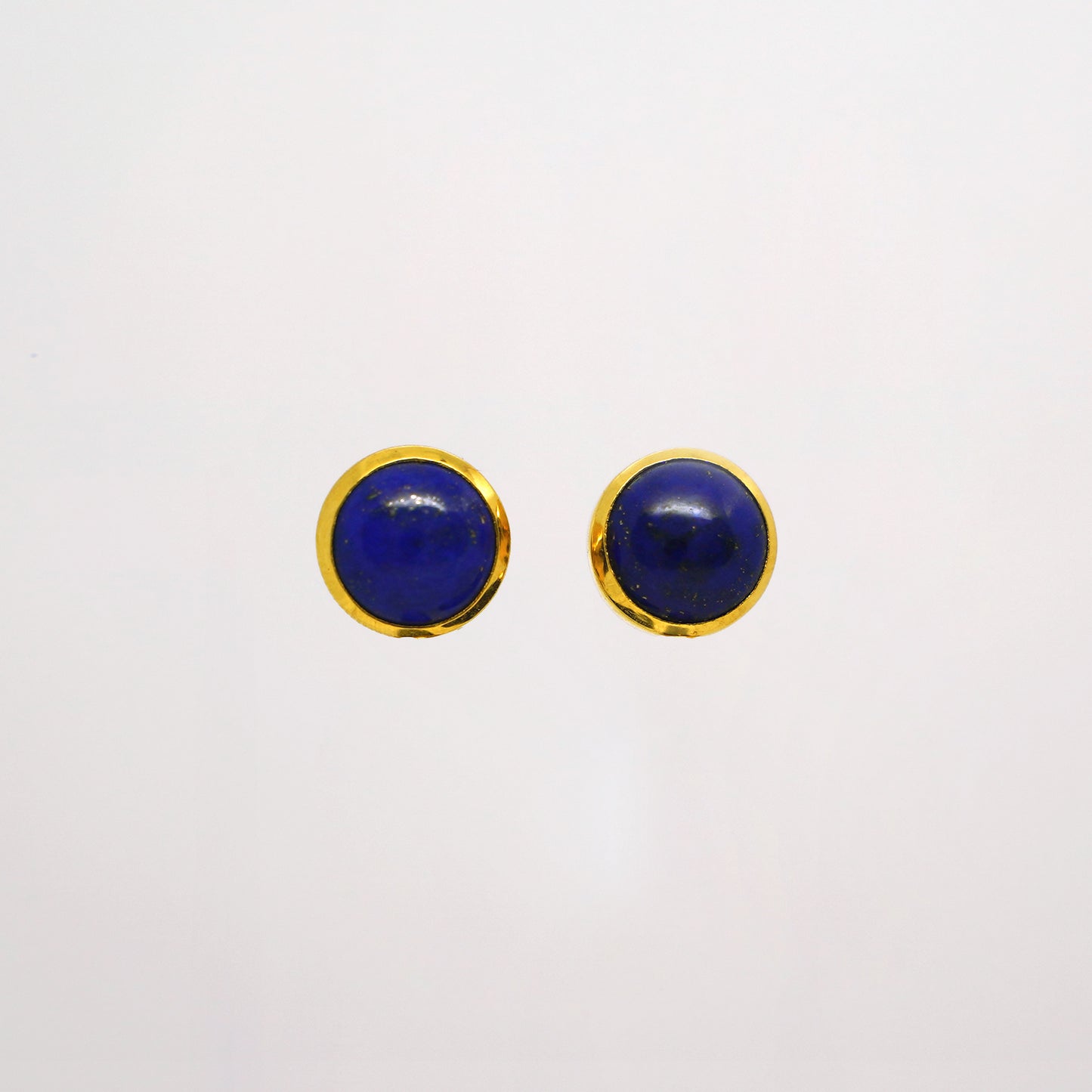 Pair of round blue lapis lazuli studs gold earrings with gold rims on a white background