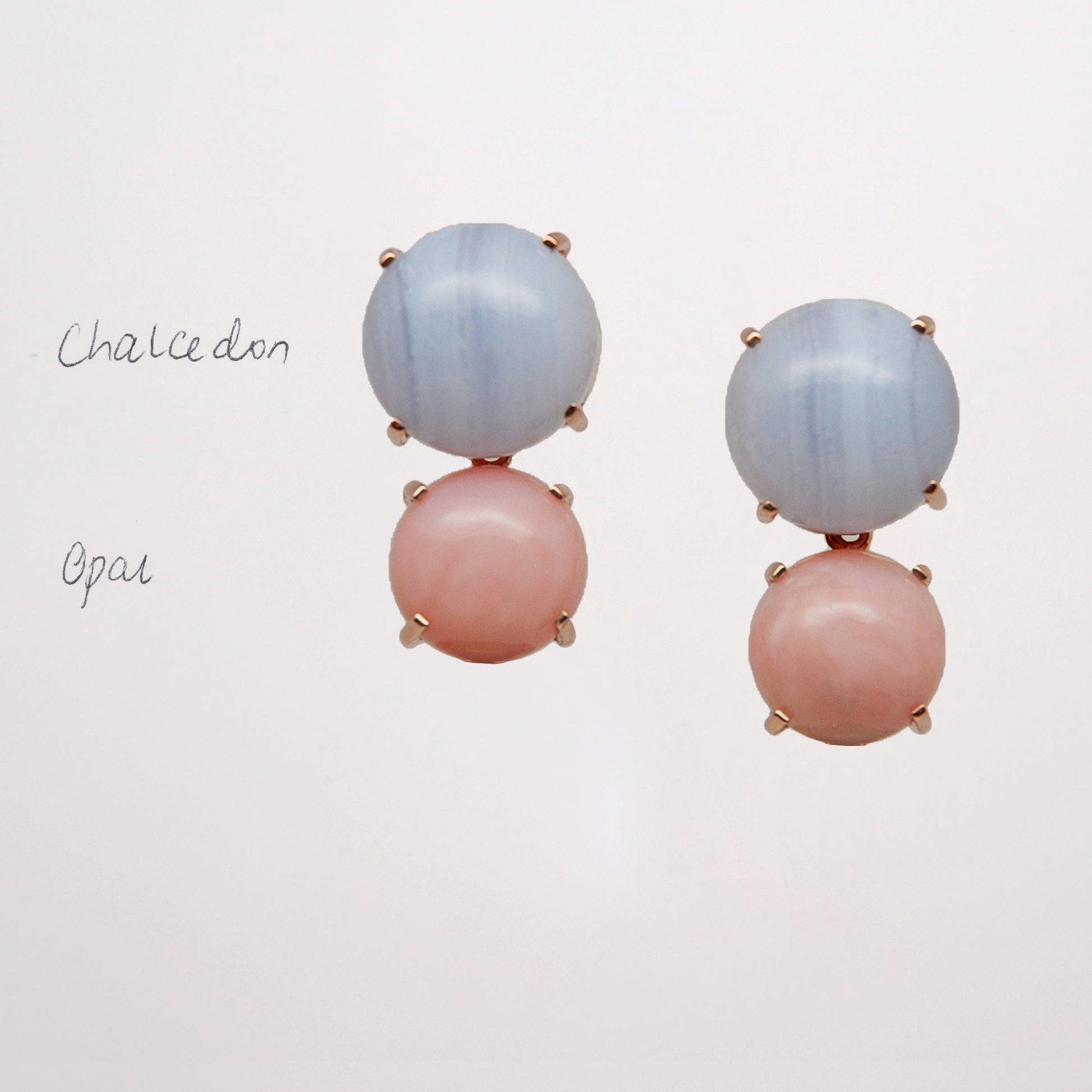 Pair of earrings with pink and blue gemstone on a light gray background